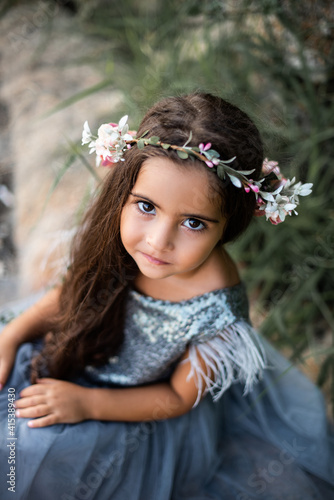 Summertime vacations in thailand. Beautiful little girl with wreath and in dress looks at camera posing in calming seacoast.