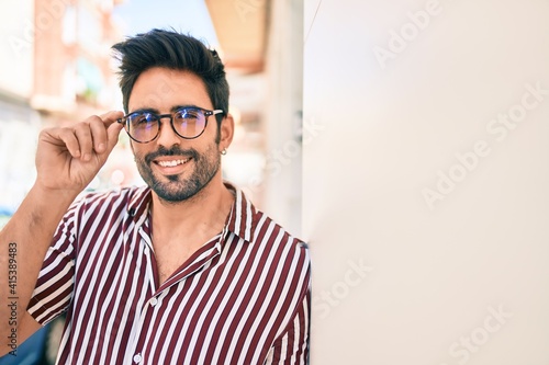 Young handsome hispanic man with beard wearing glasses smiling happy outdoors