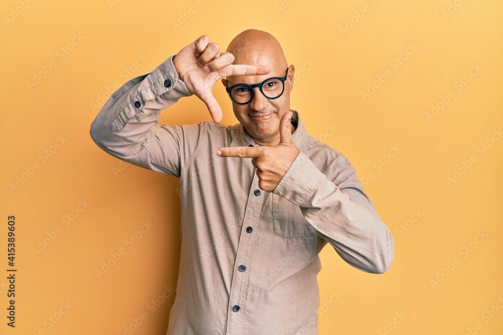 Fototapeta premium Middle age bald man wearing casual clothes and glasses smiling making frame with hands and fingers with happy face. creativity and photography concept.