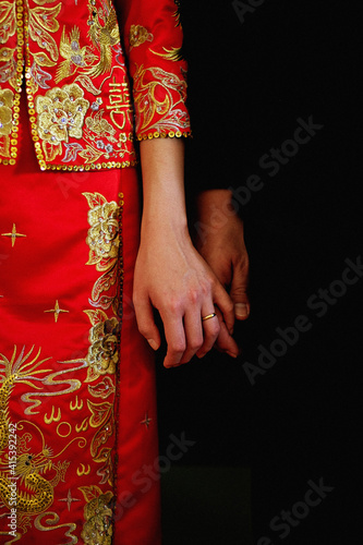 Midsection Of A Chinese Newlywed Wearing Traditional Wedding Dress, Standing And Holding Hands In The Wedding Ceremony.