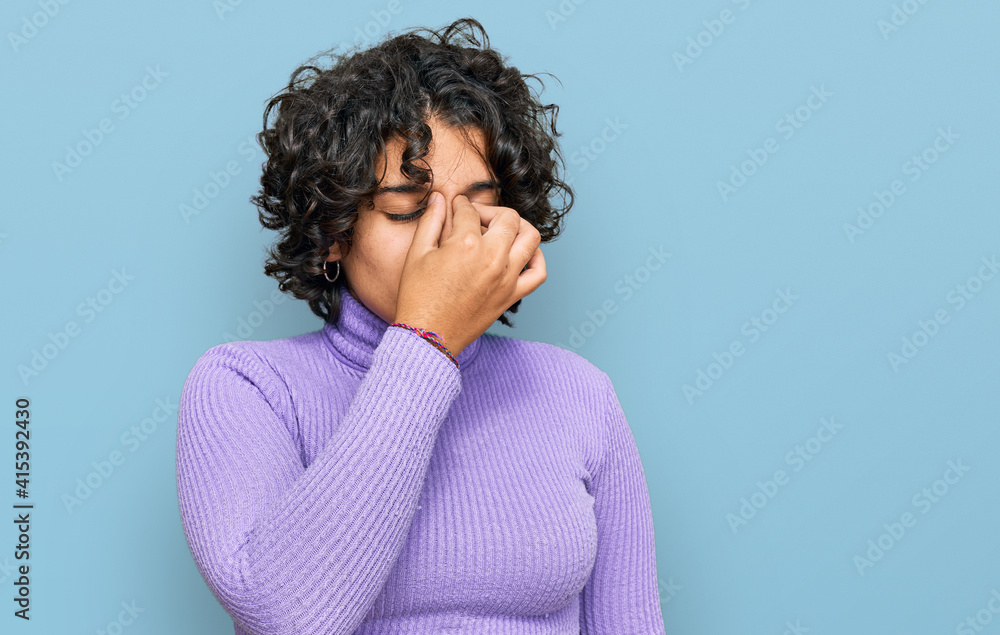 Young hispanic woman with curly hair wearing casual clothes tired rubbing nose and eyes feeling fatigue and headache. stress and frustration concept. Young hispanic woman with curly hair wearing casual clothes tired rubbing nose and eyes feeling fatigue and headache. stress and frustration concept.