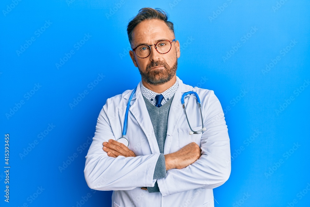 Handsome middle age man wearing doctor uniform and stethoscope skeptic and nervous, disapproving expression on face with crossed arms. negative person. Handsome middle age man wearing doctor uniform and stethoscope skeptic and nervous, disapproving expression on face with crossed arms. negative person.