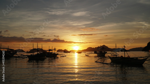 Sunset over the ocean with boats at El Nido Beach in Philippines.