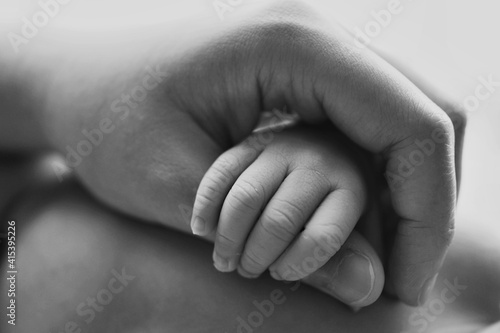 Cropped shot of baby boy holding mother's hand, black and white image.