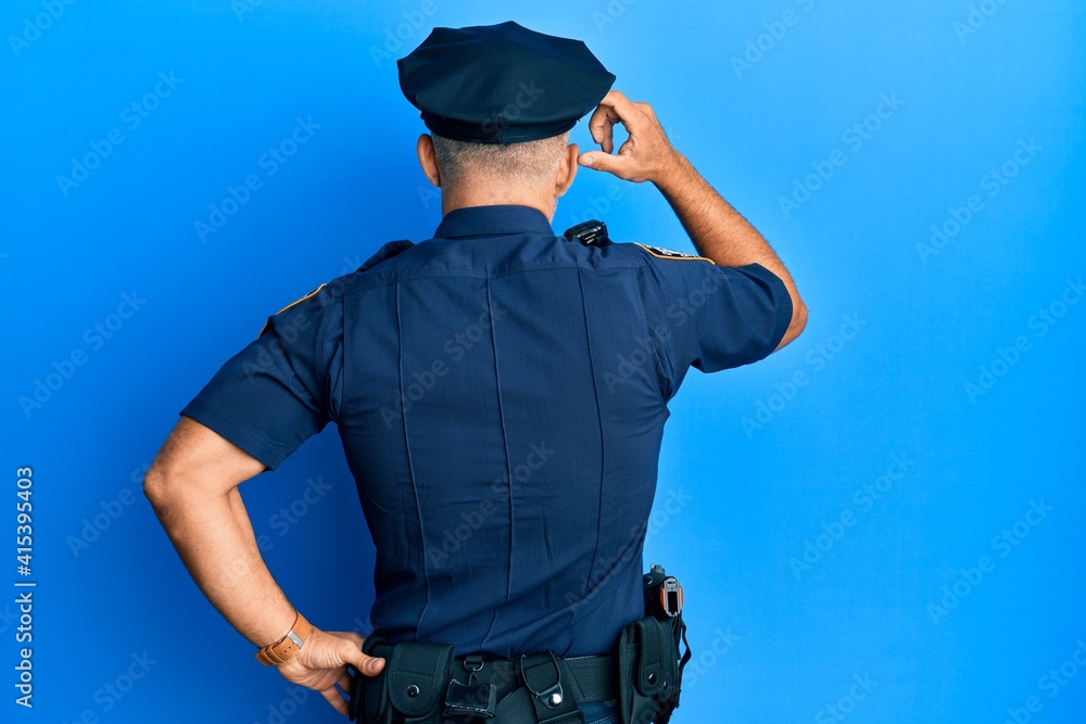 Middle age handsome man wearing police uniform backwards thinking about doubt with hand on head Middle age handsome man wearing police uniform backwards thinking about doubt with hand on head
