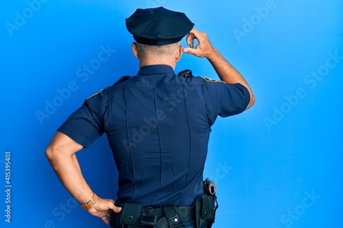 Middle age handsome man wearing police uniform backwards thinking about doubt with hand on head
