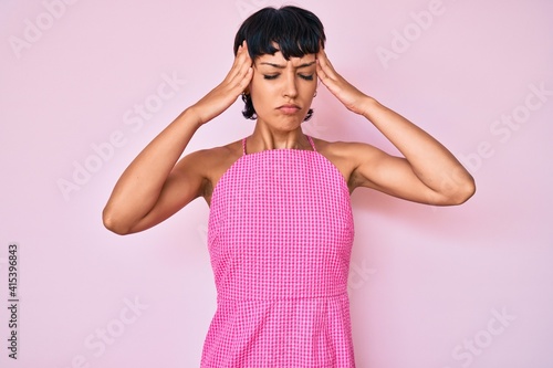 Beautiful brunettte woman wearing casual clothes over pink background with hand on head, headache because stress. suffering migraine.