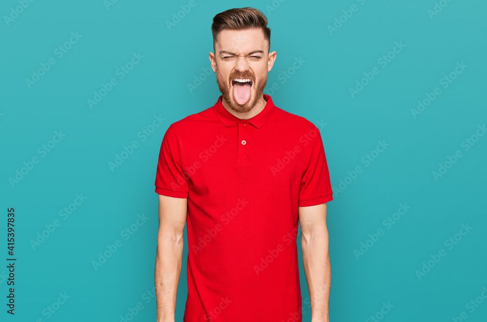 Young redhead man wearing casual clothes sticking tongue out happy with funny expression. emotion concept. Young redhead man wearing casual clothes sticking tongue out happy with funny expression. emotion concept.