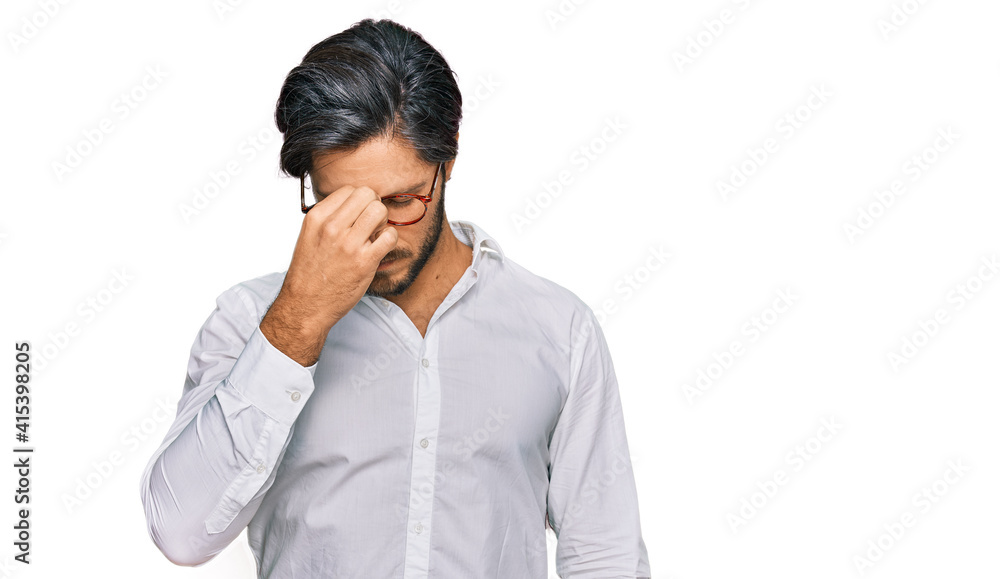 Young hispanic man wearing business shirt and glasses tired rubbing nose and eyes feeling fatigue and headache. stress and frustration concept. Young hispanic man wearing business shirt and glasses tired rubbing nose and eyes feeling fatigue and headache. stress and frustration concept.