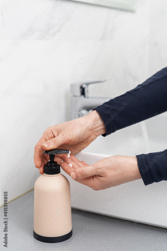 Woman washing hands with soap in bathroom