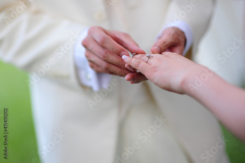 Groom putting a ring on the bride's finger during the wedding ceremony. © ltyuan