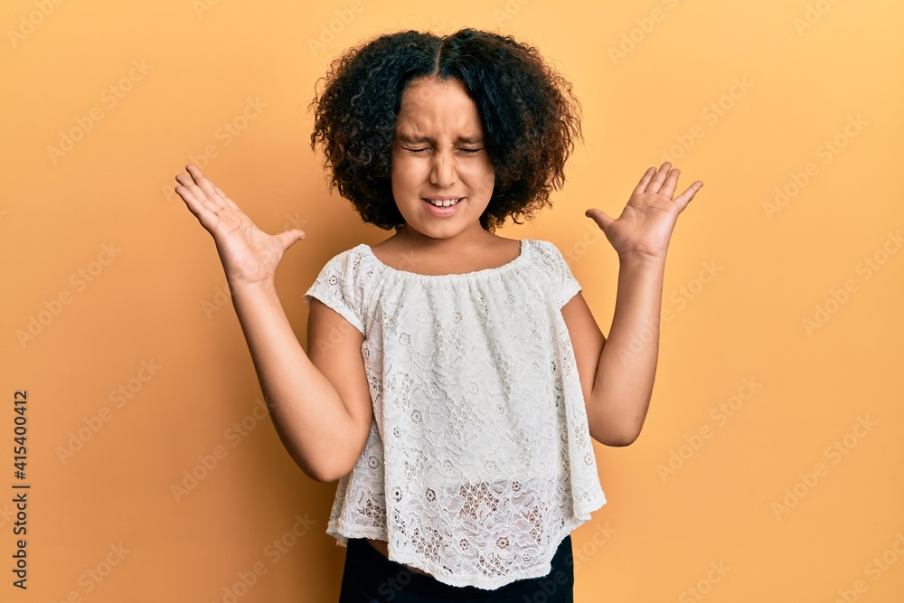 Young little girl with afro hair wearing casual clothes celebrating mad and crazy for success with arms raised and closed eyes screaming excited. winner concept Young little girl with afro hair wearing casual clothes celebrating mad and crazy for success with arms raised and closed eyes screaming excited. winner concept