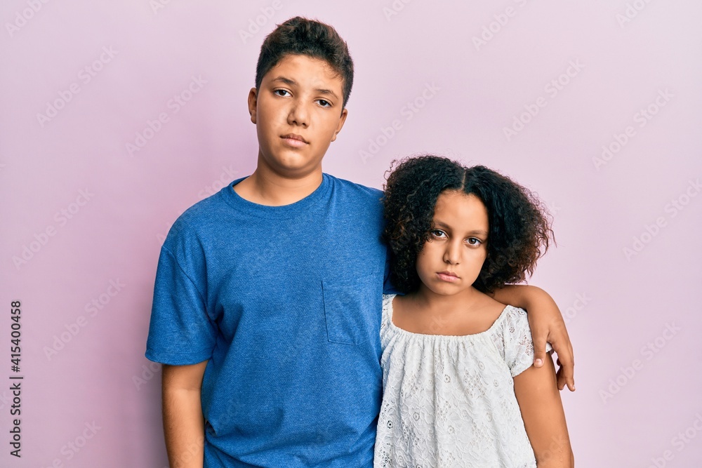 Young hispanic family of brother and sister wearing casual clothes together relaxed with serious expression on face. simple and natural looking at the camera. Young hispanic family of brother and sister wearing casual clothes together relaxed with serious expression on face. simple and natural looking at the camera.