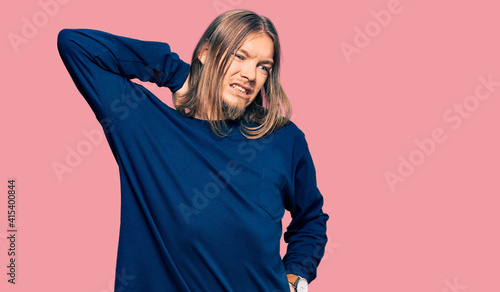 Handsome caucasian man with long hair wearing casual winter sweater suffering of neck ache injury, touching neck with hand, muscular pain © Krakenimages.com