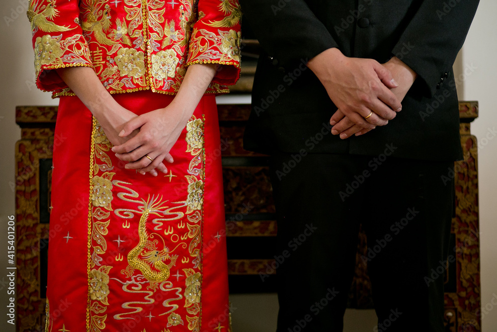 Midsection of Chinese bride and groom wearing traditional Chinese wedding costumes.