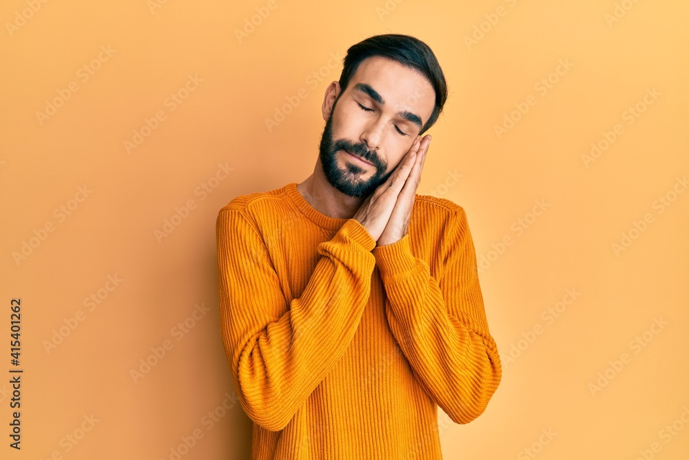 Young hispanic man wearing casual clothes sleeping tired dreaming and posing with hands together while smiling with closed eyes. Young hispanic man wearing casual clothes sleeping tired dreaming and posing with hands together while smiling with closed eyes.