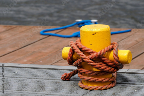 yellow metal bitteng with a coiled brown cable on the pier close side view photo