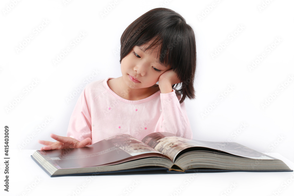 Cute little child girl reading a book on the desk, isolated on white background. Cute little child girl reading a book on the desk, isolated on white background.