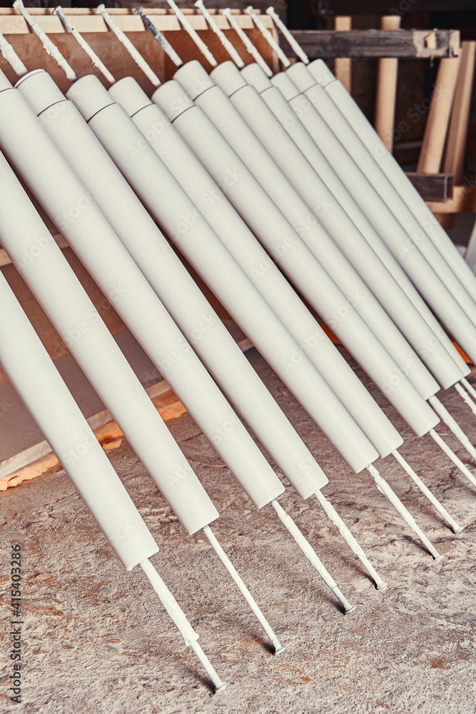 Collection of new wooden furniture legs drying after applying paint leaned on large rack in light woodwork shop close view Collection of new wooden furniture legs drying after applying paint leaned on large rack in light woodwork shop close view