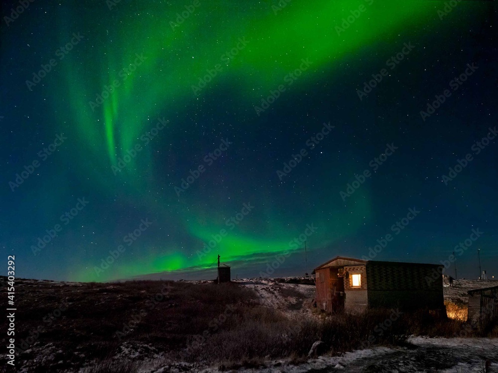 Old weather station. Winter Teriberka. Evening polar landscape with the Aurora Borealis.