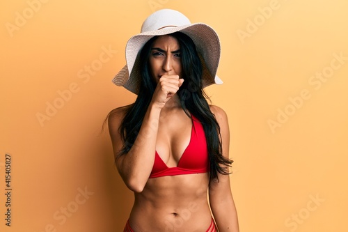 Beautiful hispanic woman wearing bikini and summer hat feeling unwell and coughing as symptom for cold or bronchitis. health care concept.