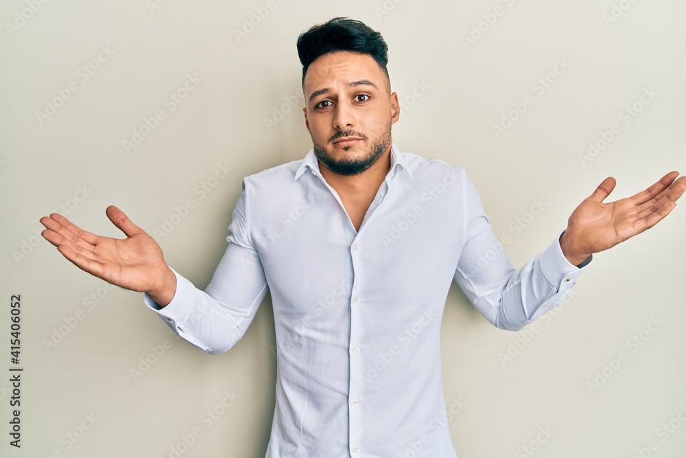 Young arab man wearing casual clothes clueless and confused with open arms, no idea and doubtful face. Young arab man wearing casual clothes clueless and confused with open arms, no idea and doubtful face.
