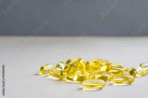 Yellow capsules are scattered on a light background.Soft focus.
