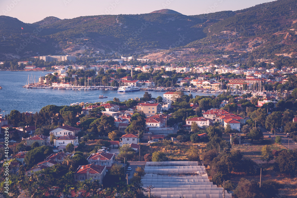 The aerial shot of old Foca (in TR: Eski Foca) in Izmir, Turkey. The Castle, harbour, yachts, seabus, houses and sea are all visible. Shot is taken in the golden hour during sunset time.
