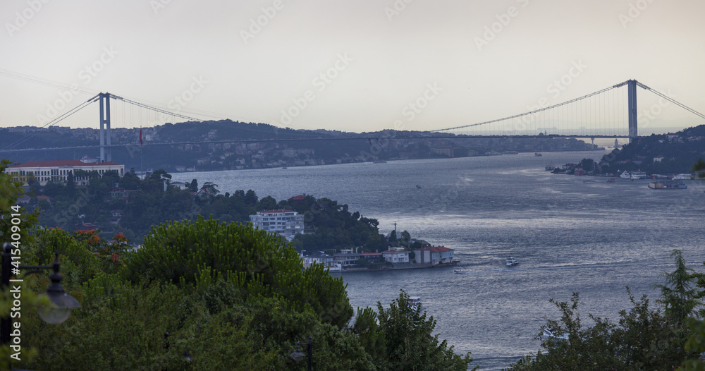 Bosporus Bridge and Maidens tower are in the same frame. Sea traffic in Istanbul strait. Maiden tower under the leg of Bosporus Bridge. Sunset time in Istanbul. Bosporus Bridge and Maidens tower are in the same frame. Sea traffic in Istanbul strait. Maiden tower under the leg of Bosporus Bridge. Sunset time in Istanbul.