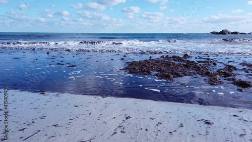 Small waves roll onto the shore with bundles of algae. Villasimius, Sardinia island
