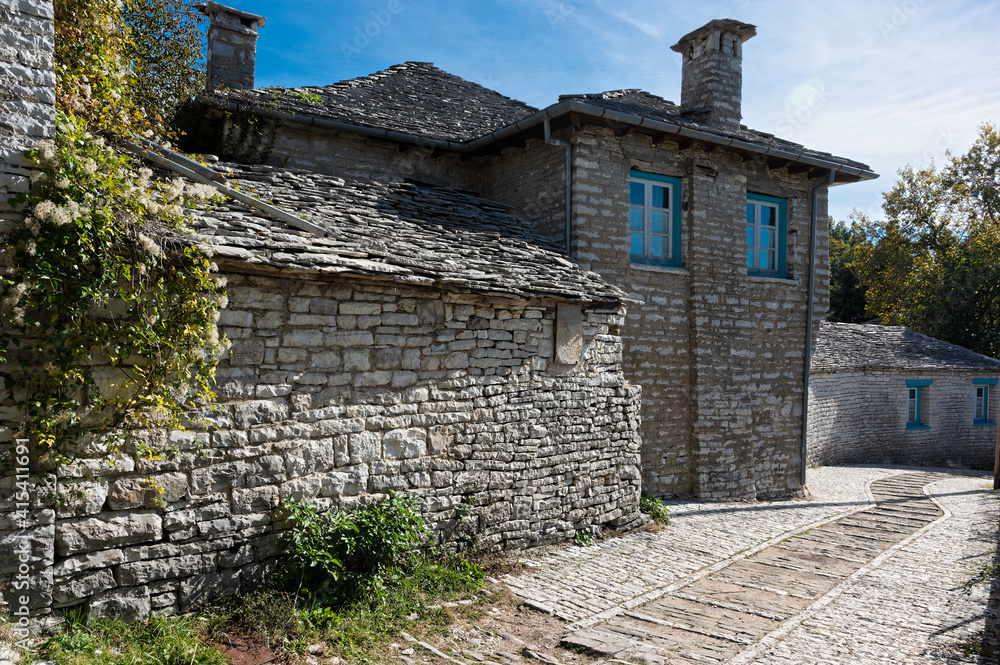 Stone houses of traditional architecture and cobble-stone narrow street in the village of Papigo in Epirus, Greece Stone houses of traditional architecture and cobble-stone narrow street in the village of Papigo in Epirus, Greece