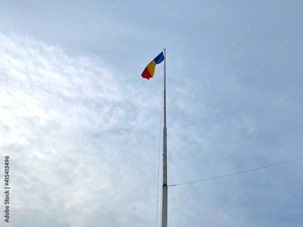 Naklejka premium The National flag of Romania winding on a blue sky background