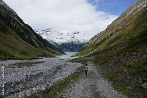 a woman hiking at the Schlegeis Stausee in the High Alps Nature Park, Zillertal Alps, Tirol, Austria, September