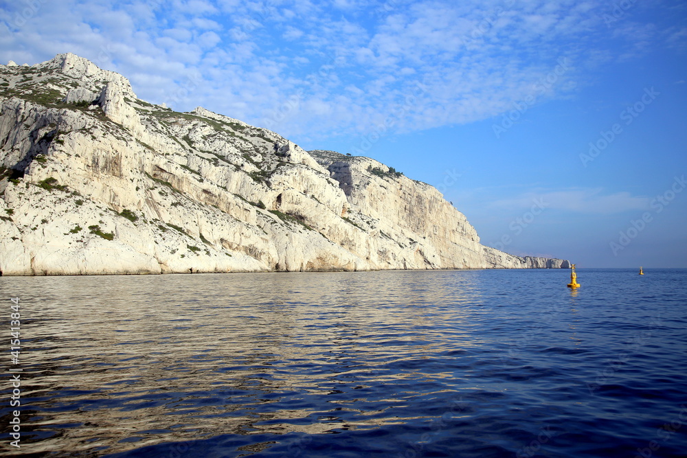 Cliff with diagonal fracture lines, in the blue Mediterranean sea and under the cloudy sky, Parc National des Calanques, Marseille, France