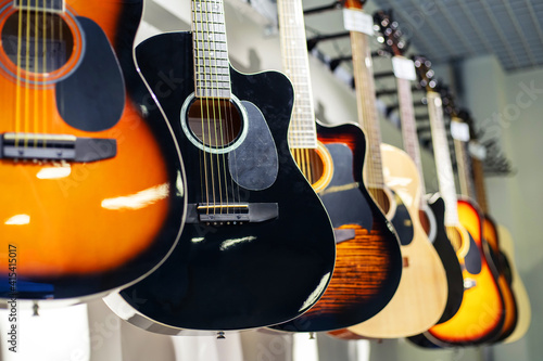 Acoustic guitars of different colors and types on a musical instrument store window. Foreground. Selective focus