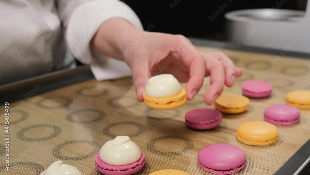 Pastry chef is filling cream chocolate macarons with pastry bag, close up. Pastry chef is filling cream chocolate macarons with pastry bag, close up.