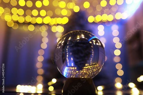 Crystal Ball on the floor with bokeh, lights behind. Glass ball with colorful bokeh light, new year celebration concept.