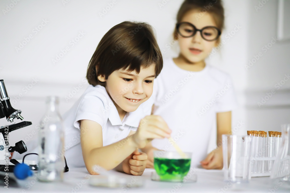 Two cute children at chemistry lesson making experiments on white background Two cute children at chemistry lesson making experiments on white background