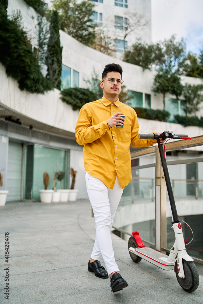 young man with a scooter drinking coffee young man with a scooter drinking coffee
