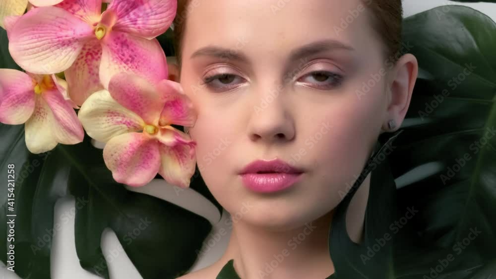 Closeup face of young beautiful woman with a healthy clean skin. Beautiful white girl with big green leaves. Beauty and spa treatment concept. Pretty woman with natural makeup and plant near face. Closeup face of young beautiful woman with a healthy clean skin. Beautiful white girl with big green leaves. Beauty and spa treatment concept. Pretty woman with natural makeup and plant near face.