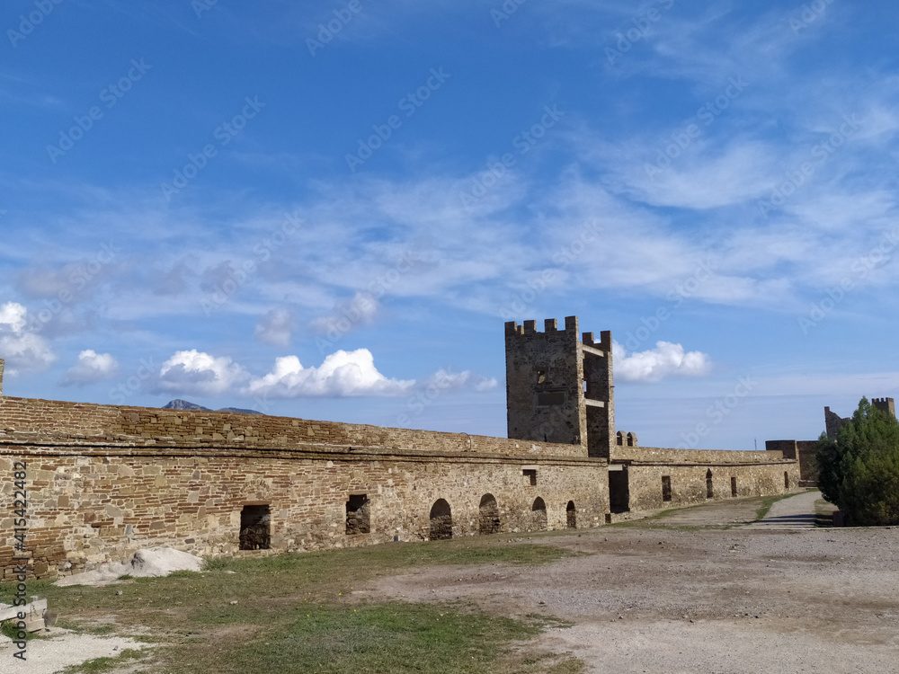 Part of the fortress wall in the city of Sudak in the Crimea against the blue sky in summer. Travel concept. Mobile photo.