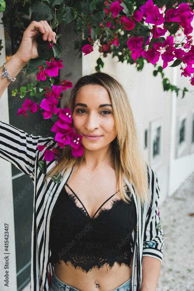beautiful girl walking and holding a branch of a red flower. spring walks around the city beautiful girl walking and holding a branch of a red flower. spring walks around the city