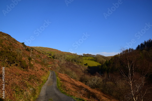 a single track road leading up to the mountains in the sunlight