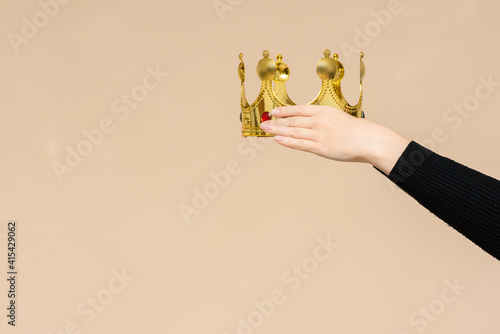 Female hands is wearing a golden crown on the copy space. Award ceremony.