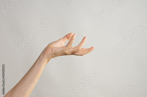 Hand gestures, Elegant female hand, pointing to the side. palm holds something, a blank for the design. light grey background