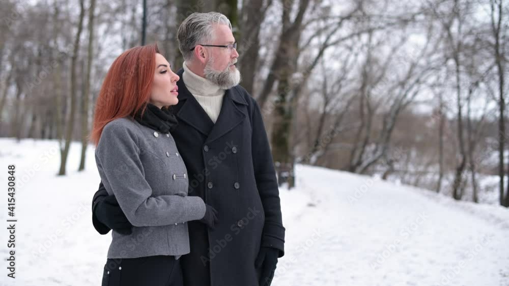Husband and wife walk in the park and enjoy the views, contemplate the landscape and enjoy a wonderful winter snowy weekend Husband and wife walk in the park and enjoy the views, contemplate the landscape and enjoy a wonderful winter snowy weekend