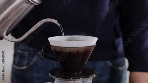 Coffee Drip Concept. Person Pouring Hot Water from Kettle into a Dripper. Making Pour Over Hot Coffee Drink in House. Zen and Cozy Living. Closeup shot