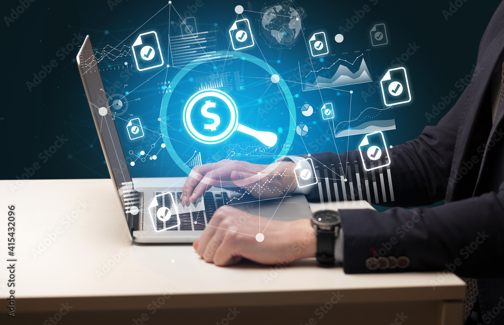Business hand working on laptop with magnifying glass with a dollar sign icons coming out from the screen, successful business concept Business hand working on laptop with magnifying glass with a dollar sign icons coming out from the screen, successful business concept