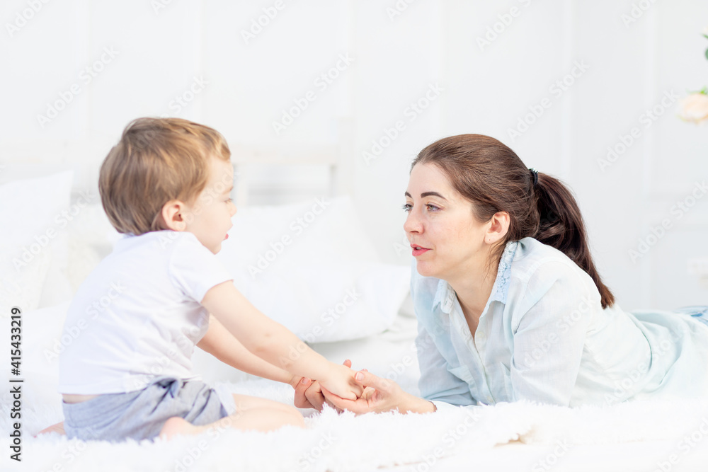mom and baby talking at home on the bed, the concept of the relationship between parents and children mom and baby talking at home on the bed, the concept of the relationship between parents and children