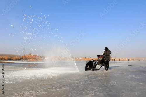 Farmers use electric saws to cut river ice in the wild. © zhang yongxin